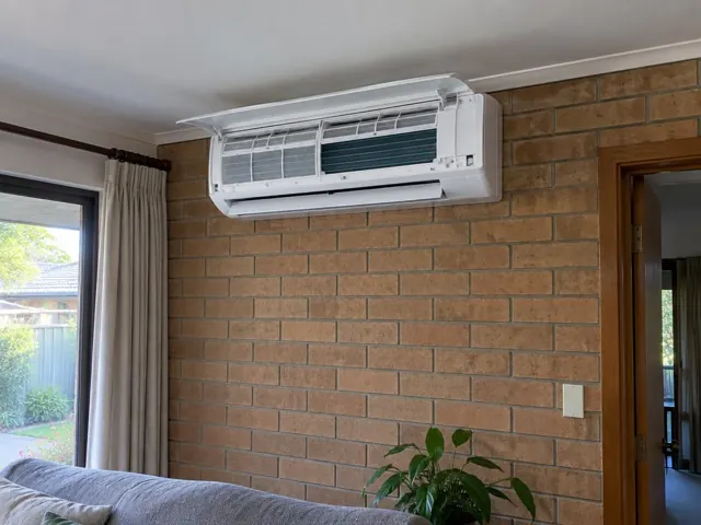 Clean wall-mounted split system on a brick wall with open front panel and visible filters in Golden Grove