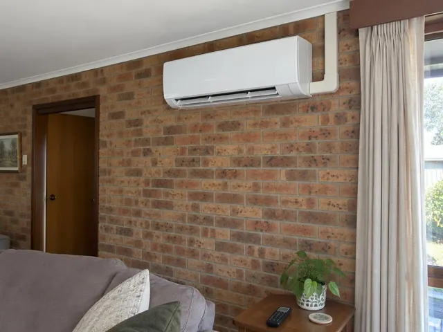 Indoor split system mounted high on a brick living room wall with louvre open in Redwood Park