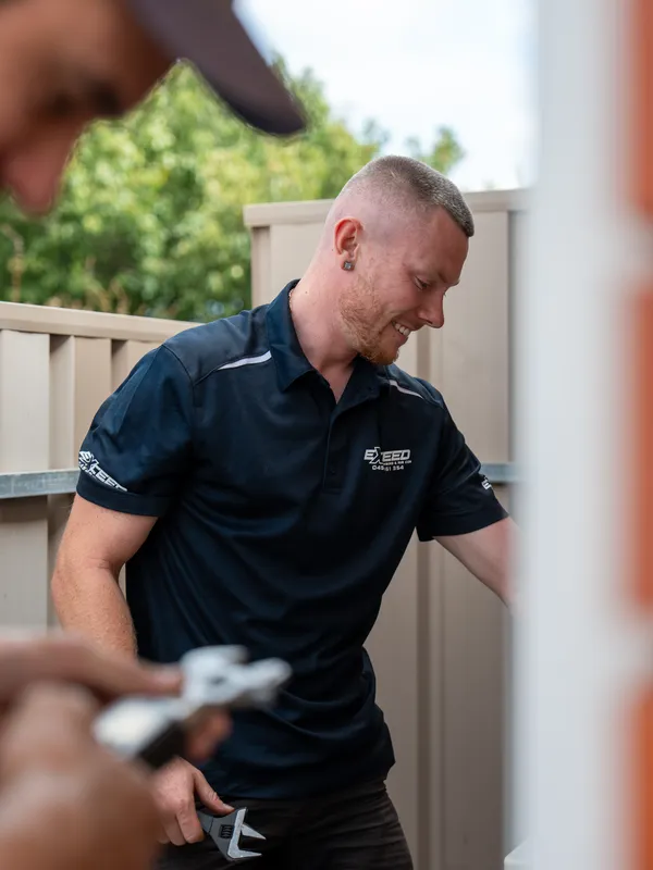 Technician with a wrench, smiling mid-job